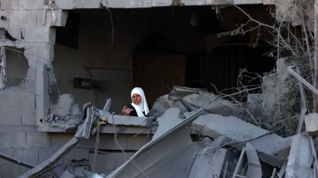 A woman sits among rubble in Gaza