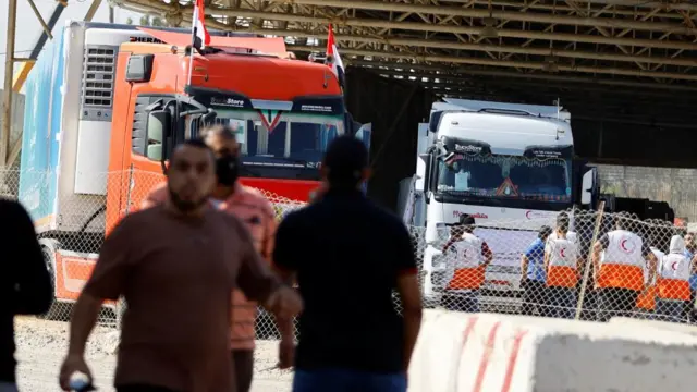 Aid workers oversee aid trucks entering Gaza through the Rafah crossing