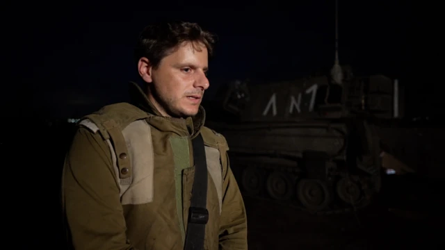 Israeli solider stands next to a tank in the dark