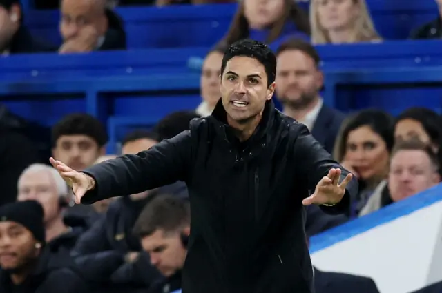 Arteta waves his hands at his players from the touchline.