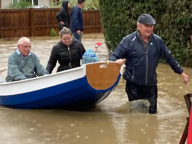 A small boat being used to rescue people in a flooded street