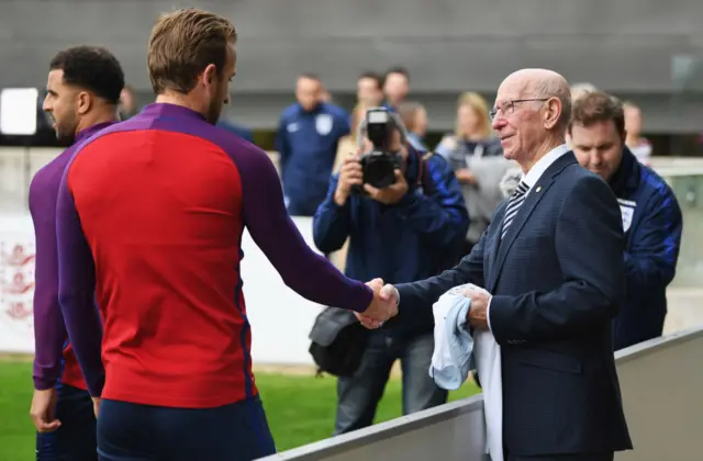 Harry Kane shakes the hand of Sir Bobby Charlton