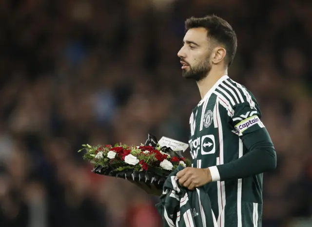 Fernandes carries a tribute wreath for Sir Bobby Charlton.