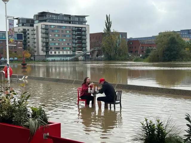 Two Five Guys workers eating food in the middle of flooding in Lincolnshire