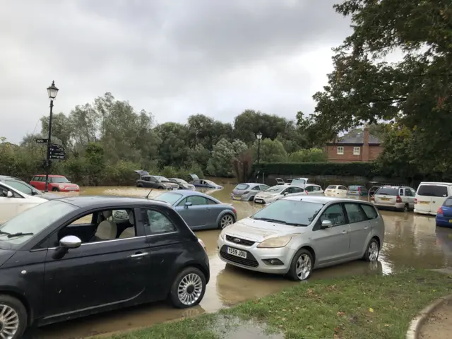 The Elms car park in Framlingham still partially flooded. Dirt marks on car bonnets show how high the water had been.