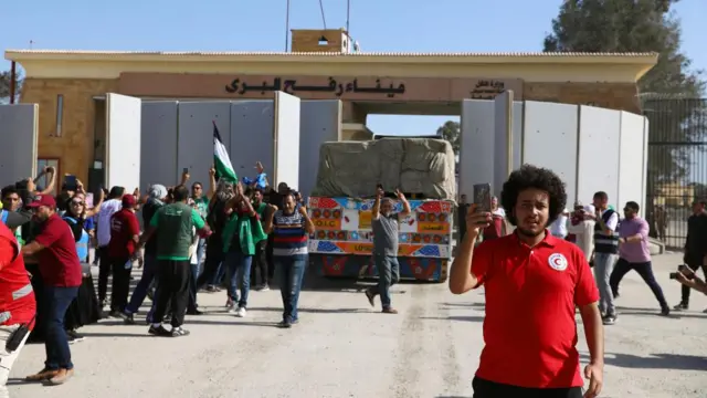 People celebrate as a truck passes through the gate at the border