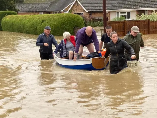 A small boat being used to rescue people in a flooded street