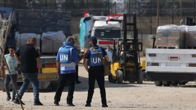 Two UN workers oversee aid being transferred between trucks