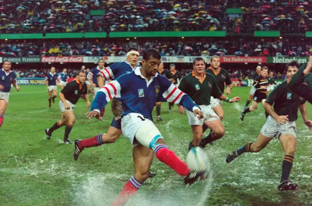 Emile Ntamack kicks the ball on a very wet pitch