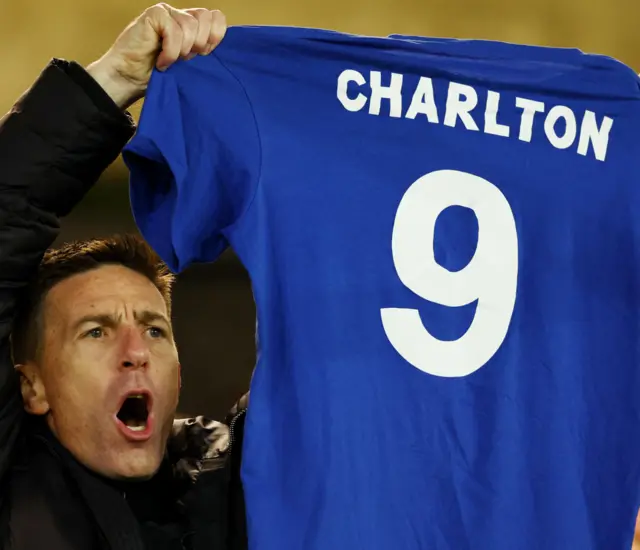 A fan holds up a Charlton 9 top during the tribute.