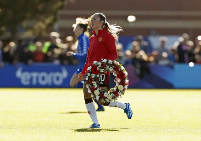 Katie Zelem carries a wreath following the passing of former Manchester United player Bobby Charlton