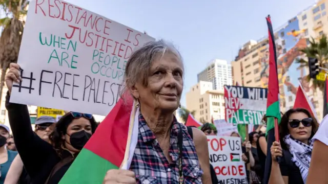 A group of people in Los Angeles attend a pro-Palestine march, holding signs and flags