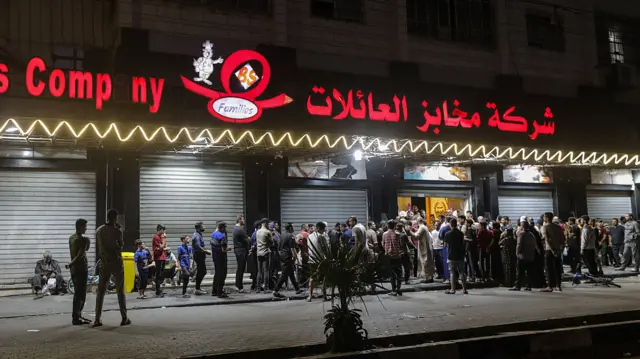 Gaza residents line up to receive bread outside a bakery in Gaza City