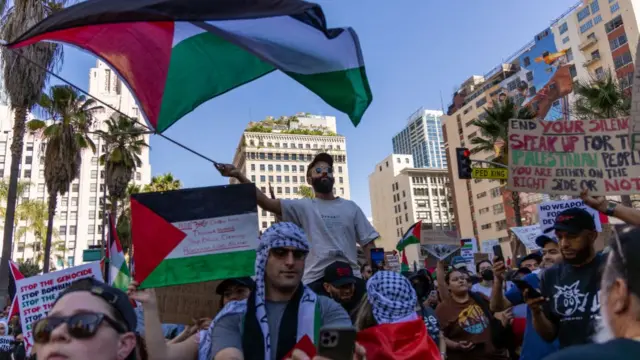 A group of people march through Los Angeles waving flags and holding signs