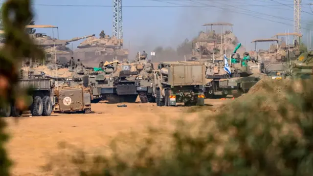 Tanks and other military vehicles line up near the barrier with Gaza