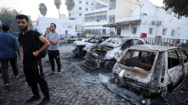 People inspect the area of Al-Ahli hospital