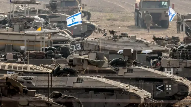 Israeli flags fly over a line of tanks