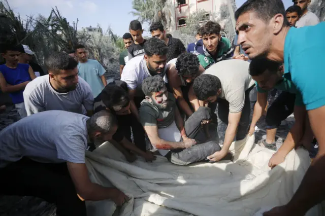 An injured man is lifted onto a sheet following a strike in Deir al-Balah