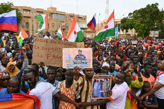 A supporter of Niger's CNSP holds a placard of Niger's new military ruler, General Abdourahamane Tiani, as they gather at Place de la Concertation in Niamey - 20 August 2023