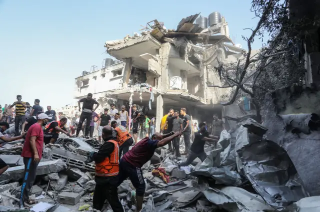 Emergency workers and civilians dig through the rubble of a building in the city of Rafah