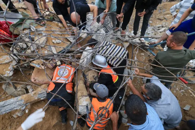 Rescuers look for survivors in the rubble of a building following Israeli strikes in Khan Younis