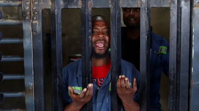 A mine worker at the entrance of the Gold One mine, where the National Union of Mineworkers says more than 500 employees are being held against their will