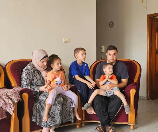 Ibrahim AlAagha sits with family members