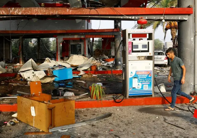 Palestinian walks past a petrol station that was hit in an Israeli strike