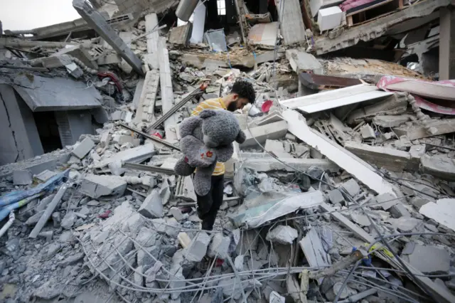 People conduct a search and rescue operation for Palestinians stuck under the debris of a destroyed building of Abu Hasanain family