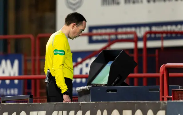 Referee Colin Steven studies the VAR monitor