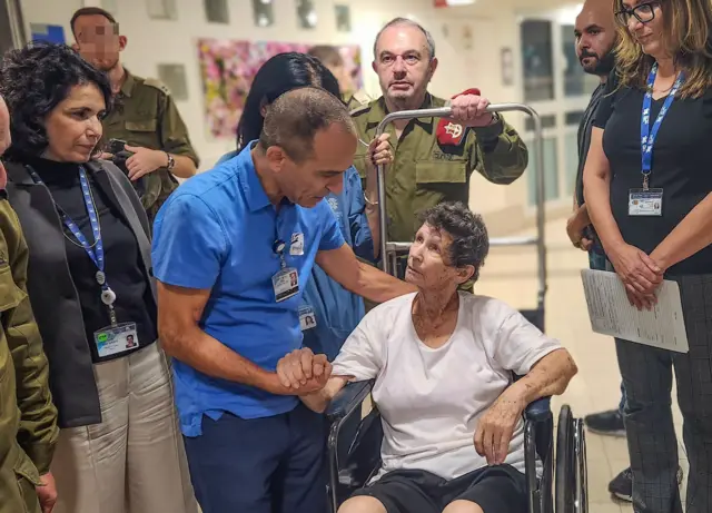 Yocheved Lifshcitz shaking hands with a hospital worker, she is sitting in a wheelchair