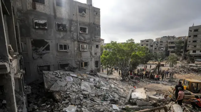 Palestinian civil defence workers search for victims and survivors among the rubble of a destroyed family house in Gaza City