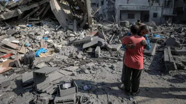 Two men hug among the rubble following a strike in Gaza