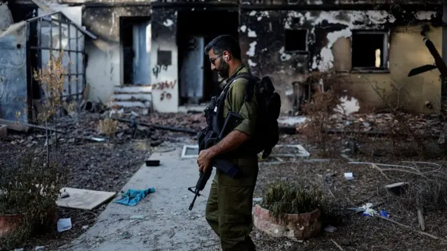 An Israeli soldier walks past a house that was damaged following a deadly attack by Hamas gunmen from the Gaza Strip, in Kibbutz Beeri, southern Israel, October 25, 2023. REUTERS/Ammar Awad