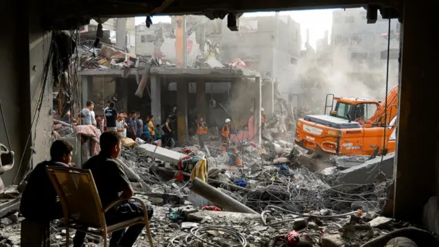 Palestinians search for casualties at the site of strikes on houses in Khan Younis in the southern Gaza Strip