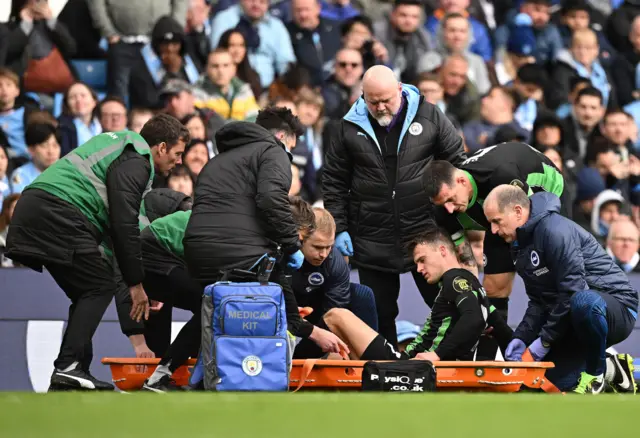 Solly March receives treatment at Manchester City before being carried off on a stretcher