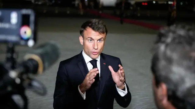 Emmanuel Macron speaks to reporters on a runway