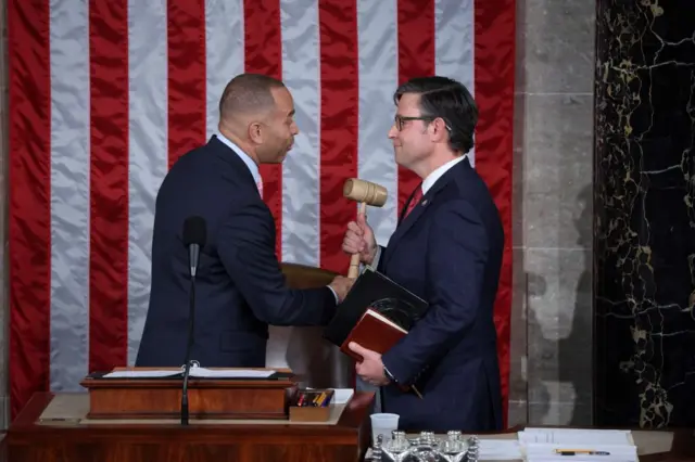 Hakeem Jeffries, House minority leader, hands the new House Speaker, Mike Johnson, the gavel