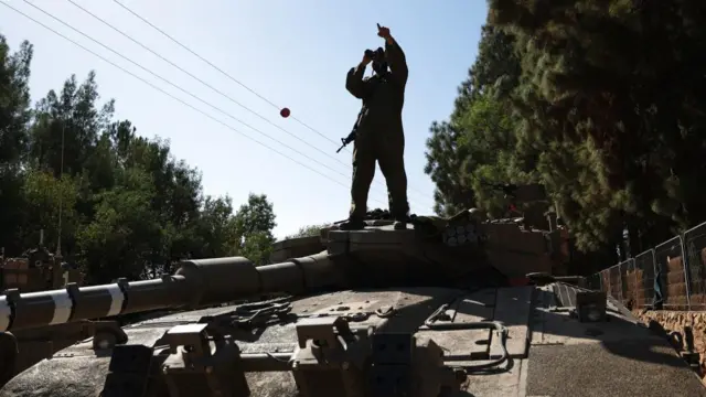 An Israeli soldier stands on a tank at Israel's border with Lebanon, in northern Israel