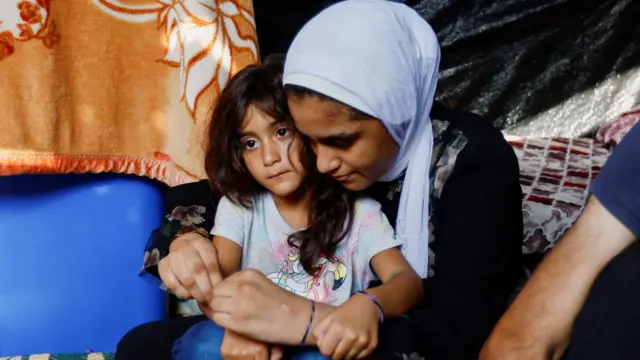 Two Palestinian girls wear bracelets given to them by their father to help identify them in fear of them being killed