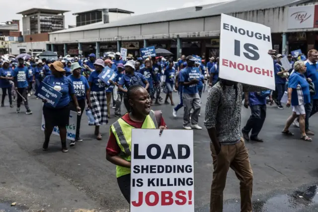 Democratic Alliance (DA) members hold placards as they march to Luthuli House, the headquarters of the ruling African National Congress (ANC), during a protest against prolonged energy crisis that has seen South Africans experience record power cuts, in Johannesburg on January 25, 2023.