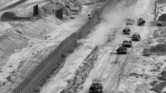 A grainy black and white image showing tanks driving