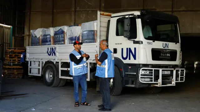 Workers stand by a United Nations vehicle, while sorting aid to be distributed to Palestinians, as the conflict between Israel and Palestinian Islamist group Hamas continues, at a United Nations-run facility, in Khan Younis in the southern Gaza Strip, October 26, 2023.