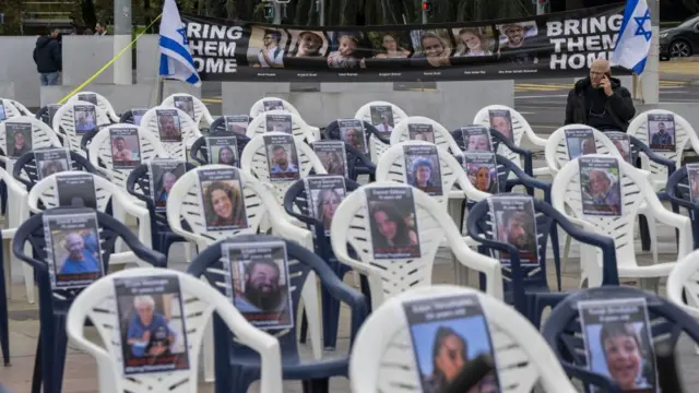 Rows of chairs with missing person posters are set up in front of a black banner that reads Bring Them Home