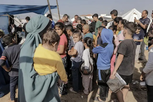 Palestinian children receive food between tents set up by United Nations Relief and Works Agency for Palestine Refugees