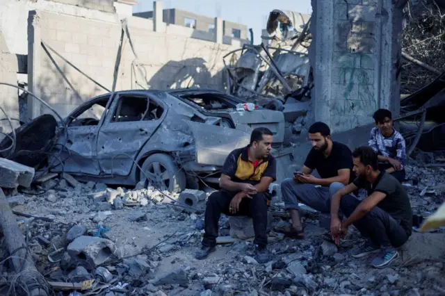 Men sit amongst the rubble in Gaza