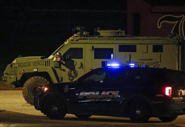 Law enforcement vehicles are parked on the Lisbon High School gymnasium as an active search for the shooter is underway following a mass shooting during