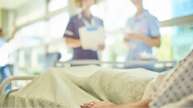 Patient in hospital bed with two nurses