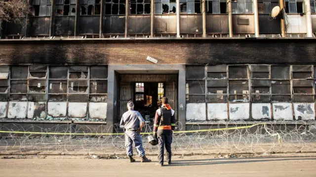 A police officer and security guard stand in front of the gutted 80 Albert Street building