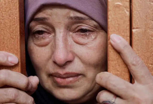 A woman crying as she stares through railings